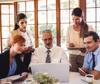 Business people discussing over laptop at table in restaurant