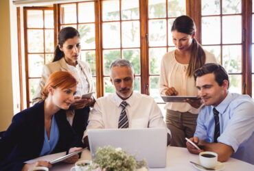 Business people discussing over laptop at table in restaurant