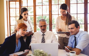 Business people discussing over laptop at table in restaurant