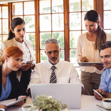 Business people discussing over laptop at table in restaurant