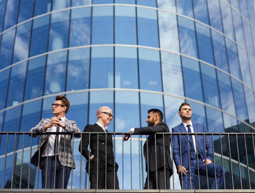 Group of young business people standing in the city with modern skyscraper in the background